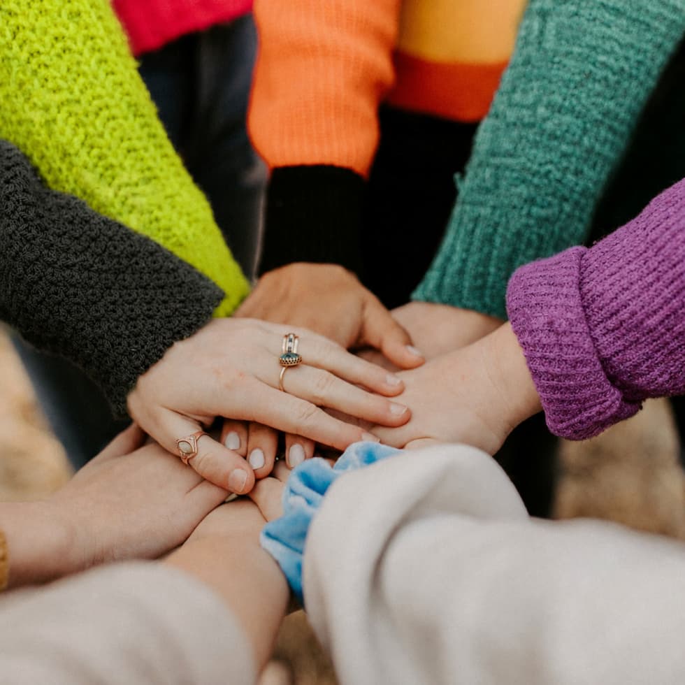Manos unidas-en-modo-equipo-con-los-colores-corporativos-de-aise